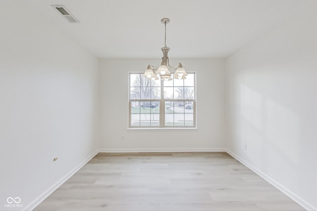 spare room featuring light hardwood / wood-style flooring and a notable chandelier