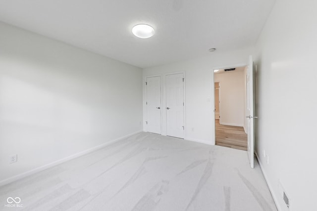 unfurnished bedroom with light carpet and a closet