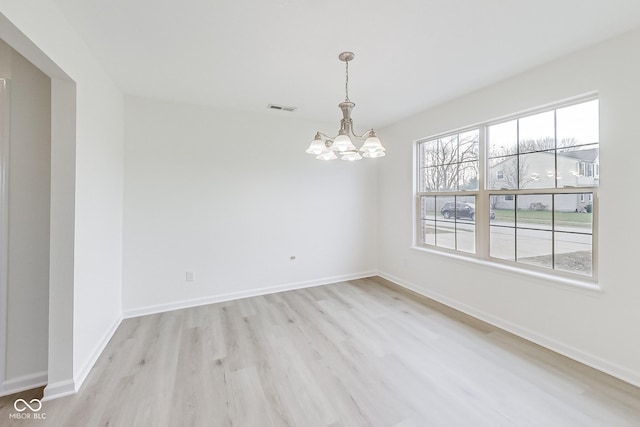 unfurnished room featuring a chandelier and light hardwood / wood-style floors