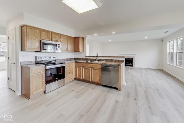 kitchen featuring kitchen peninsula, stainless steel appliances, light hardwood / wood-style flooring, and sink