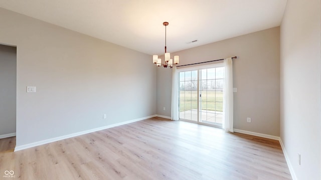 empty room with light hardwood / wood-style flooring and a chandelier