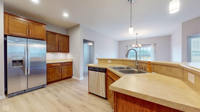 kitchen with backsplash, stainless steel appliances, sink, pendant lighting, and a chandelier