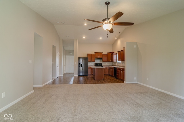 kitchen with vaulted ceiling, ceiling fan, black appliances, dark colored carpet, and a center island