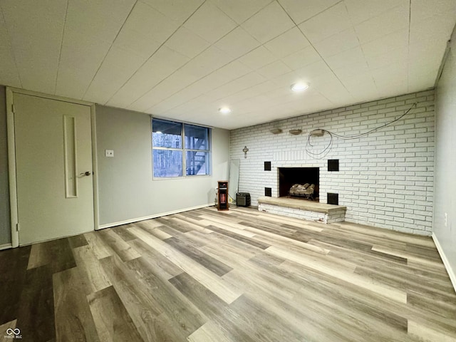 unfurnished living room featuring light wood-type flooring and a brick fireplace