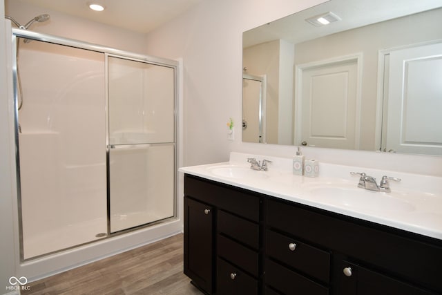 bathroom with hardwood / wood-style floors, vanity, and an enclosed shower