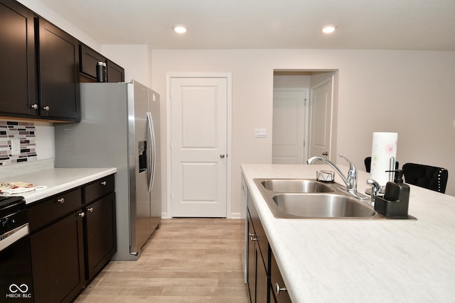 kitchen with decorative backsplash, stainless steel refrigerator with ice dispenser, dark brown cabinets, sink, and light hardwood / wood-style flooring