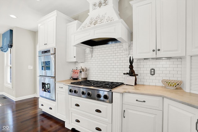 3441 S Overlook Pass, New Palestine, IN 46163 - kitchen with custom exhaust hood, stainless steel appliances, white cabinetry, dark wood-style flooring, and decorative backsplash