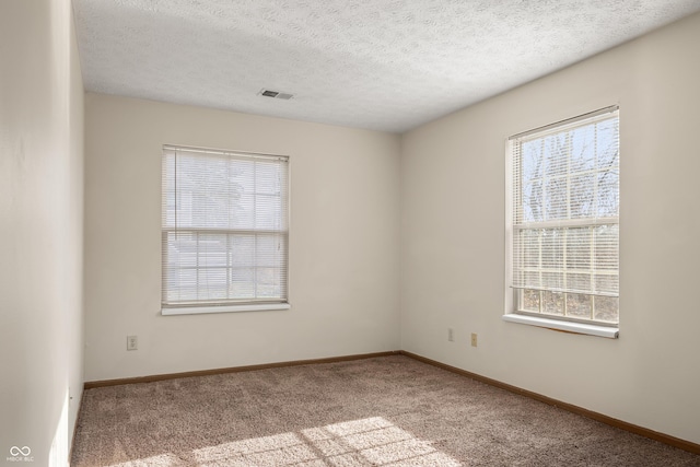 carpeted empty room with a textured ceiling