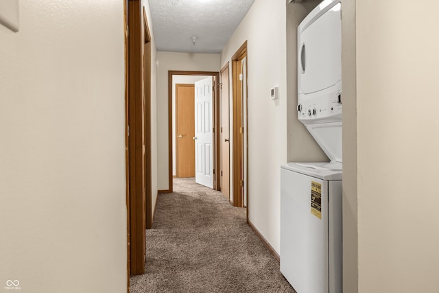 laundry area with carpet flooring, stacked washer / drying machine, and a textured ceiling