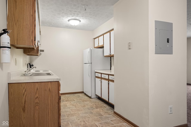 kitchen with white cabinetry, sink, electric panel, white fridge, and a textured ceiling