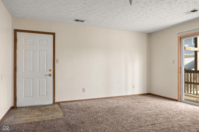 carpeted empty room featuring a textured ceiling