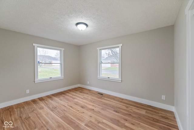 spare room featuring light hardwood / wood-style floors and a textured ceiling