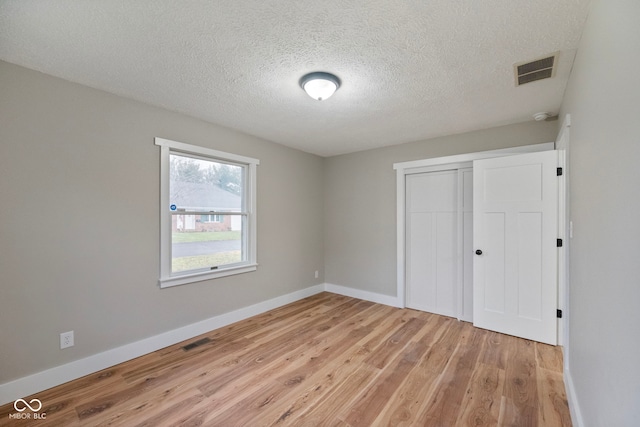 unfurnished bedroom with a closet, a textured ceiling, and light wood-type flooring