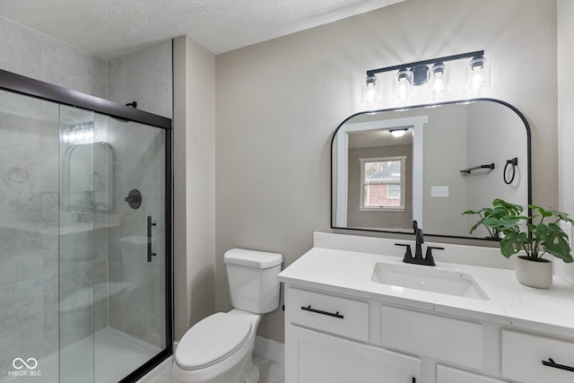 bathroom featuring vanity, toilet, a shower with shower door, and a textured ceiling