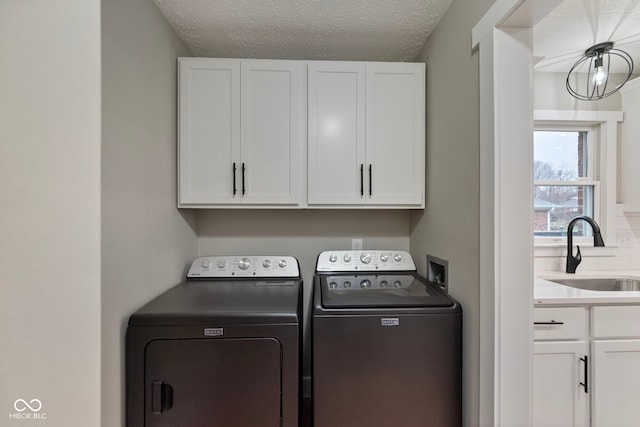 washroom with cabinets, sink, independent washer and dryer, a textured ceiling, and a chandelier