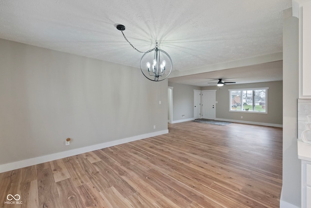 unfurnished living room featuring ceiling fan with notable chandelier, a textured ceiling, and light hardwood / wood-style floors