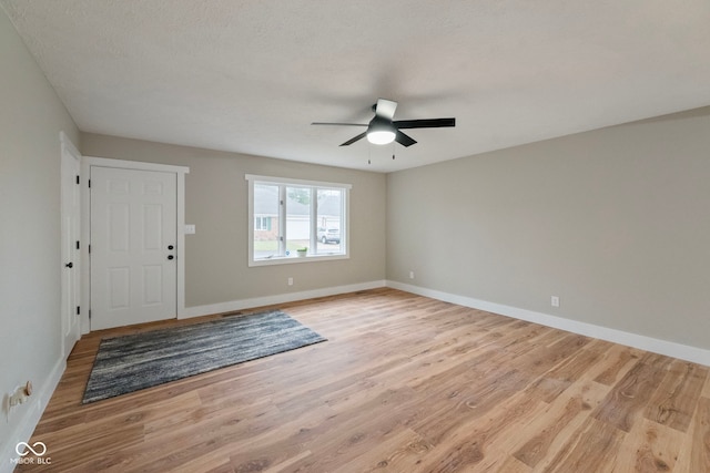 foyer entrance with a textured ceiling, light wood-type flooring, and ceiling fan