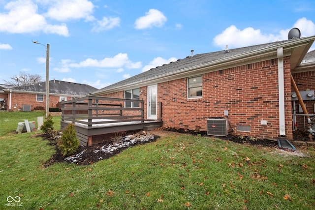 back of property with a deck, central AC unit, and a lawn