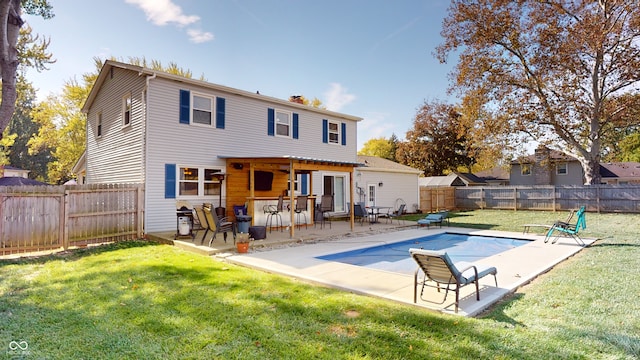 back of property featuring a patio, a covered pool, and a lawn