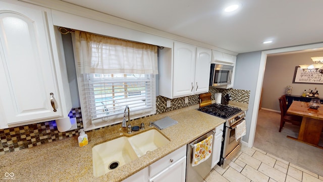 kitchen with light stone countertops, tasteful backsplash, stainless steel appliances, sink, and white cabinetry