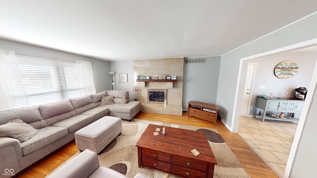 living room featuring crown molding, a fireplace, and light wood-type flooring