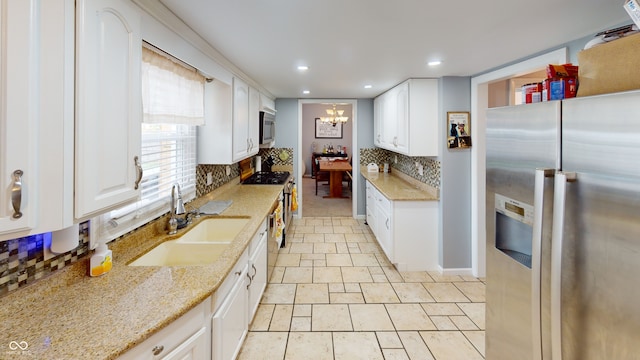 kitchen featuring light stone countertops, white cabinetry, sink, and stainless steel appliances