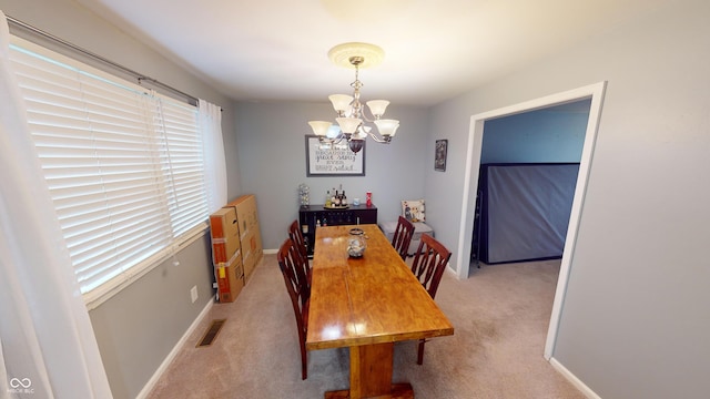 carpeted dining space with plenty of natural light and a chandelier