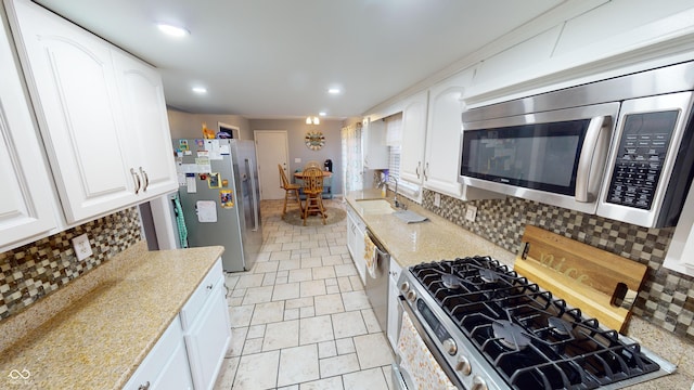 kitchen with appliances with stainless steel finishes, tasteful backsplash, white cabinetry, and sink