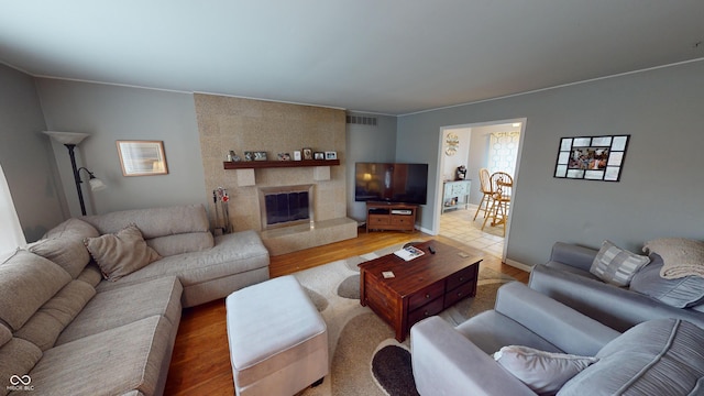 living room with a tile fireplace and wood-type flooring