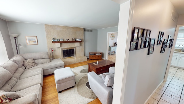 living room with sink, a large fireplace, and light wood-type flooring