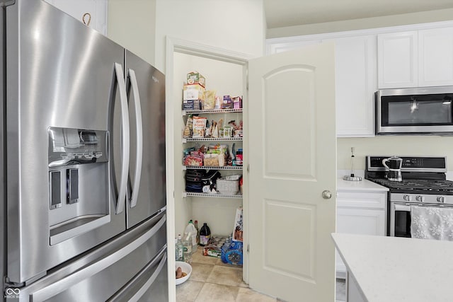 kitchen with white cabinetry, light tile patterned floors, and stainless steel appliances