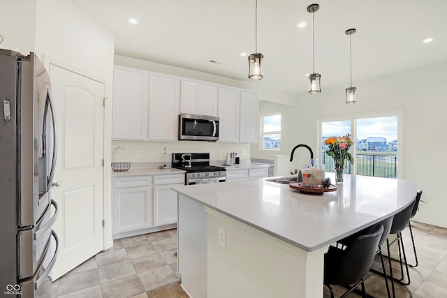 kitchen featuring white cabinets, sink, stainless steel appliances, and an island with sink