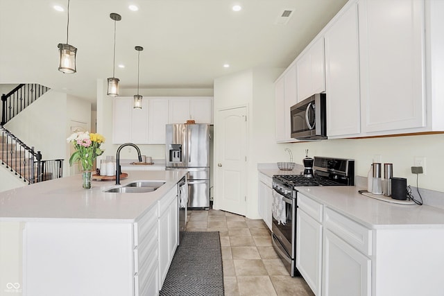 kitchen featuring appliances with stainless steel finishes, sink, pendant lighting, white cabinetry, and an island with sink