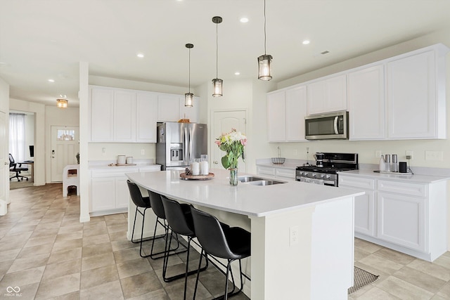 kitchen with a breakfast bar, white cabinetry, a center island with sink, and appliances with stainless steel finishes