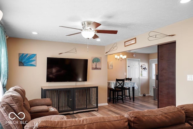 living room with hardwood / wood-style floors and ceiling fan with notable chandelier