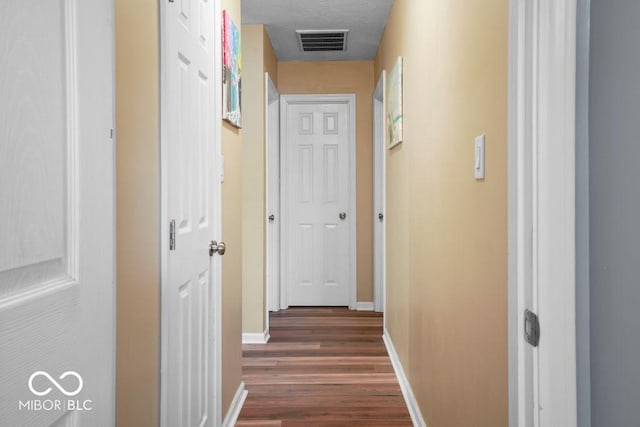 hallway with a textured ceiling and dark wood-type flooring