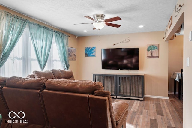 living room with ceiling fan, wood-type flooring, and a textured ceiling