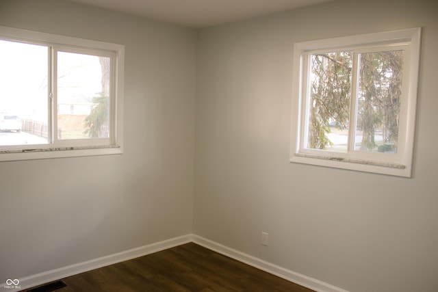 spare room with plenty of natural light and dark hardwood / wood-style floors