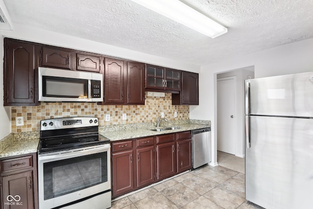 kitchen featuring sink, light stone countertops, appliances with stainless steel finishes, and tasteful backsplash