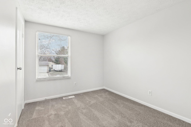 carpeted empty room featuring a textured ceiling