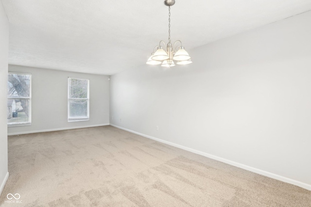 carpeted spare room featuring a chandelier