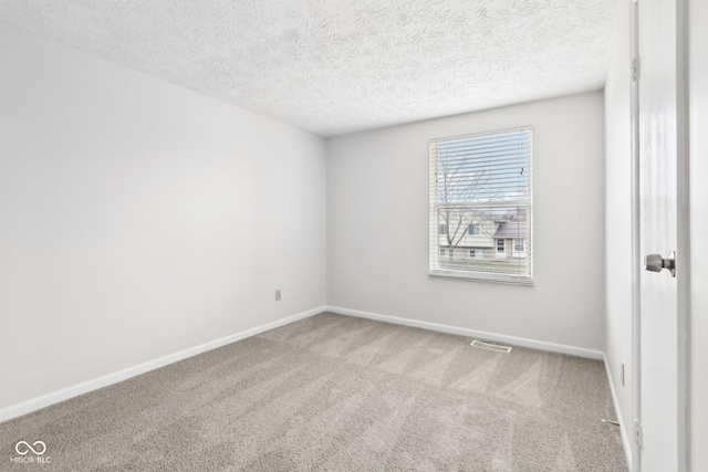 empty room with light colored carpet and a textured ceiling