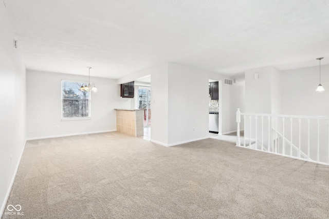 unfurnished living room with carpet and an inviting chandelier