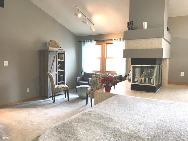 sitting room with a multi sided fireplace, rail lighting, light colored carpet, and vaulted ceiling