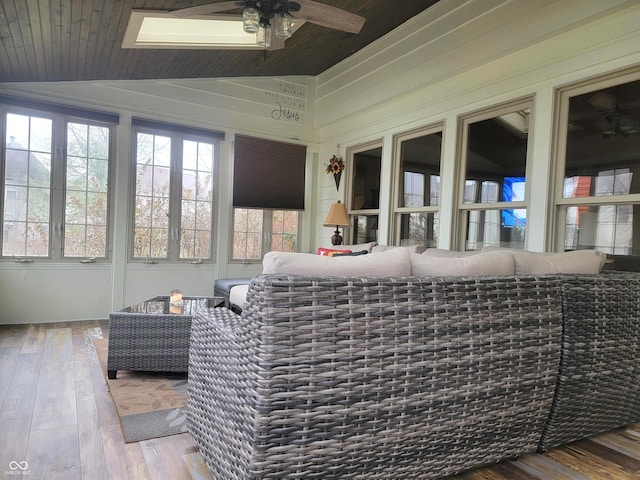 sunroom with lofted ceiling with skylight, ceiling fan, and wood ceiling