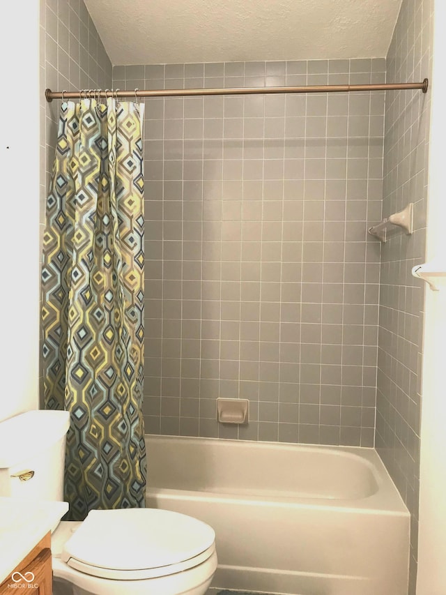 full bathroom with shower / bath combo with shower curtain, vanity, a textured ceiling, and toilet