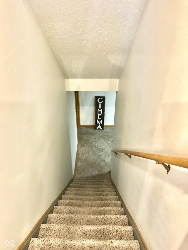 stairway with carpet and a textured ceiling