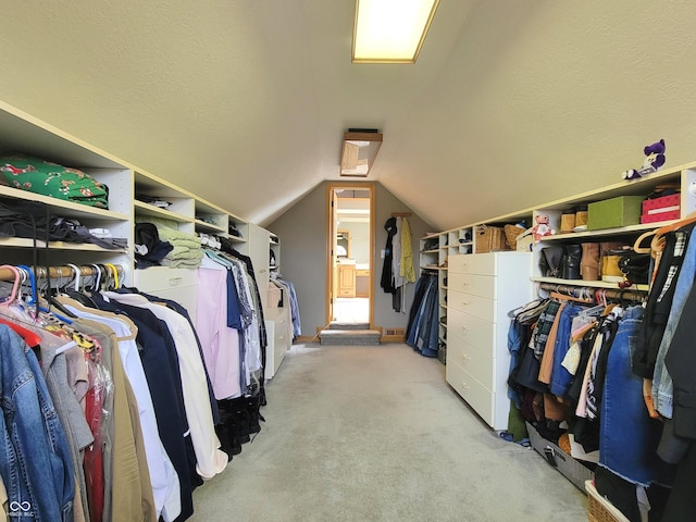 spacious closet featuring light colored carpet and lofted ceiling