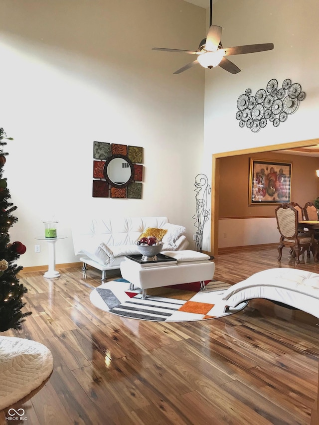 living room featuring a high ceiling, hardwood / wood-style flooring, and ceiling fan