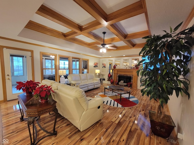 living room with ceiling fan, coffered ceiling, light hardwood / wood-style flooring, beamed ceiling, and ornamental molding